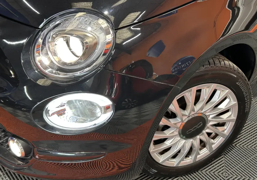 Gros plan sur l'avant droit noir du FIAT 500 2023, mettant en valeur le phare rond et la jante argentée multibranches.