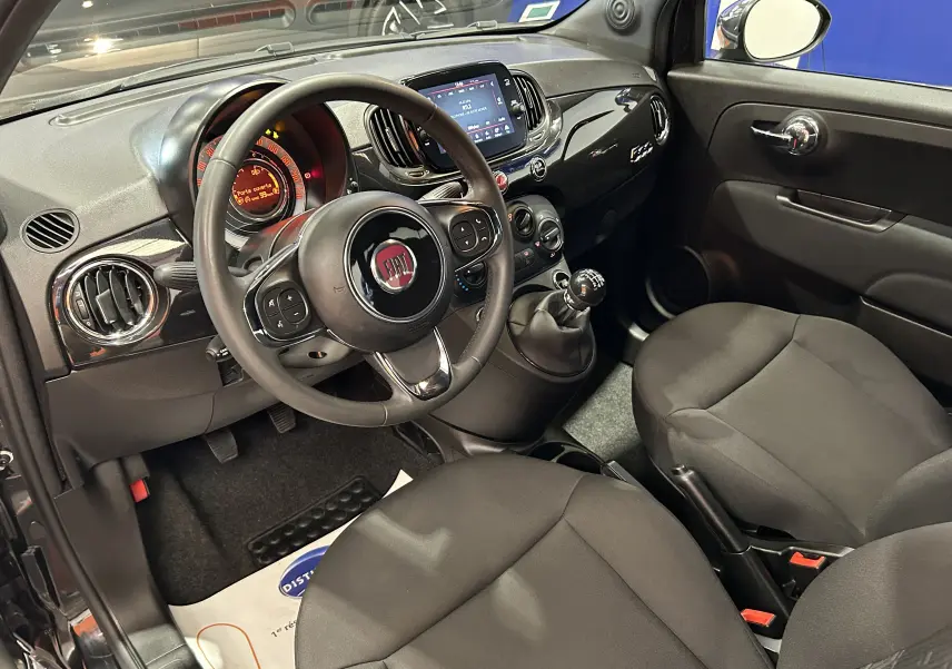 Intérieur de la Fiat 500 noir vue côté conducteur, tableau de bord avec écran tactile et volant multifonction.