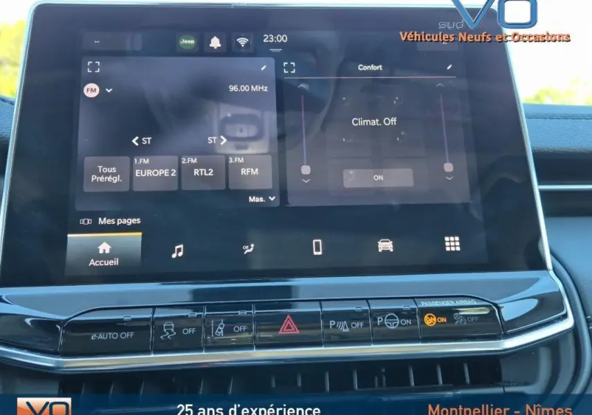 Écran tactile central du Jeep Compass gris 2024 montrant radio FM et réglages climatisation dans l'habitacle.