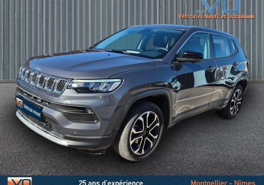 Jeep Compass gris 3/4 avant droit, jantes alliage 18 pouces, calandre distinctive et phares LED visibles.