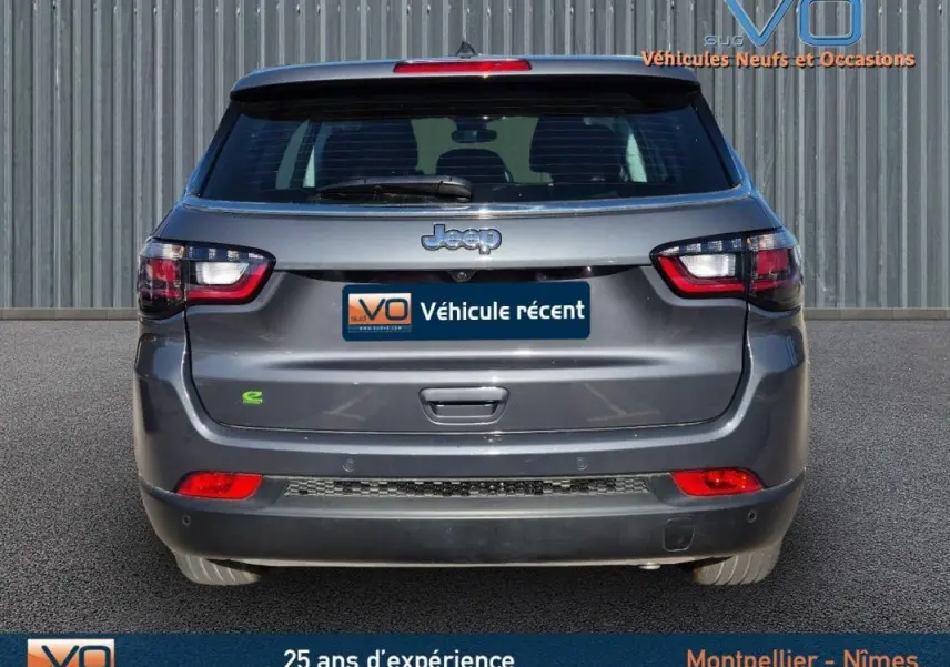 Vue arrière d'un Jeep Compass gris 2024 avec feux LED et logo Jeep bien visibles sur un fond urbain.
