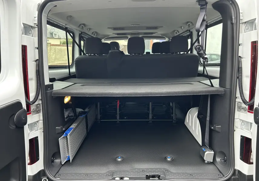 Vue arrière ouverte du Renault Trafic Combi blanc glacier, montrant l'espace de chargement et la banquette arrière noire.