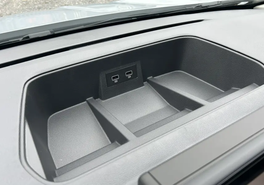 Vue rapprochée de la console de rangement noire avec deux ports USB dans le tableau de bord du Renault Trafic Combi blanc.