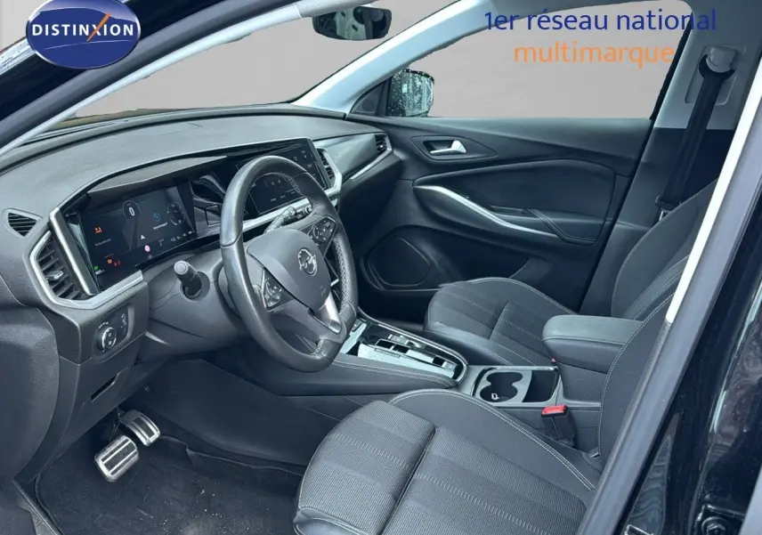 Intérieur avant droit de l’Opel Grandland noir 2024, montrant tableau de bord numérique et sièges tissu noir.