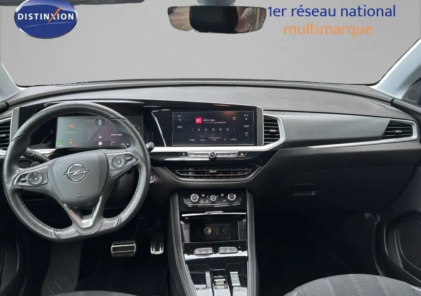 Vue intérieure frontale du tableau de bord noir de l'Opel Grandland 1.6 Turbo Hybrid 225ch avec écran tactile et volant multifonction.