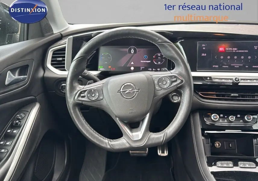 Vue intérieure centrée sur le volant noir et le tableau de bord numérique de l'Opel Grandland 1.6 Turbo Hybrid 2024.