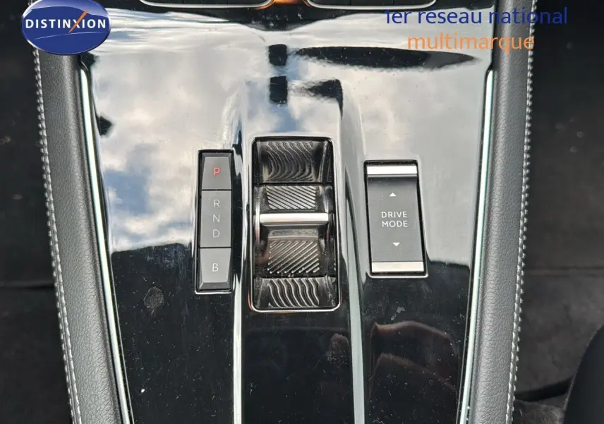 Gros plan sur la console centrale noire de l’Opel Grandland 1.6 Turbo Hybrid 225ch avec commandes de boîte auto et mode de conduite.