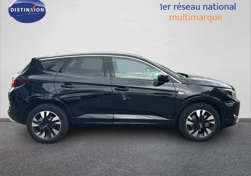 Profil droit d’un Opel Grandland 1.6 Turbo Hybrid 225ch GS noir brillant, avec jantes bi-ton et vitres teintées.