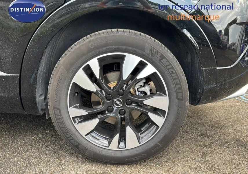 Gros plan sur la roue avant droite noire d’un Opel Grandland 2024 avec jante alliage bicolore et pneu Michelin.