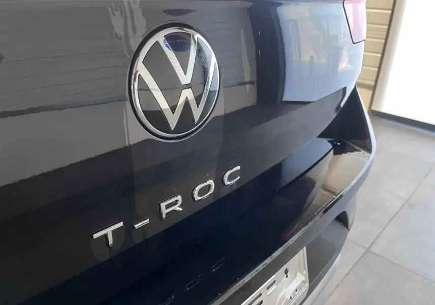 Gros plan sur l'arrière noir profond d'un Volkswagen T-Roc avec logo VW et lettrage T-ROC visible.