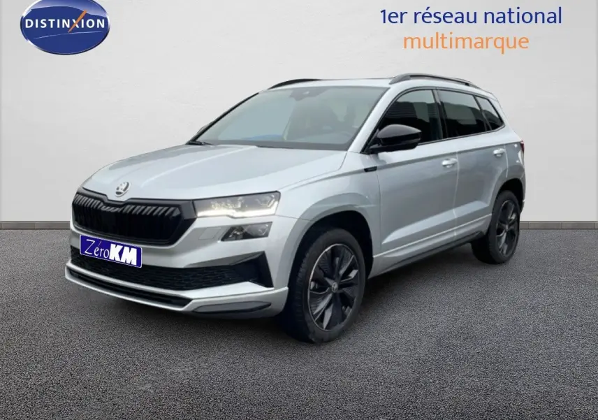 Vue 3/4 avant d’un Skoda Karoq gris argent métallisé avec calandre noire et jantes foncées, sur fond neutre.