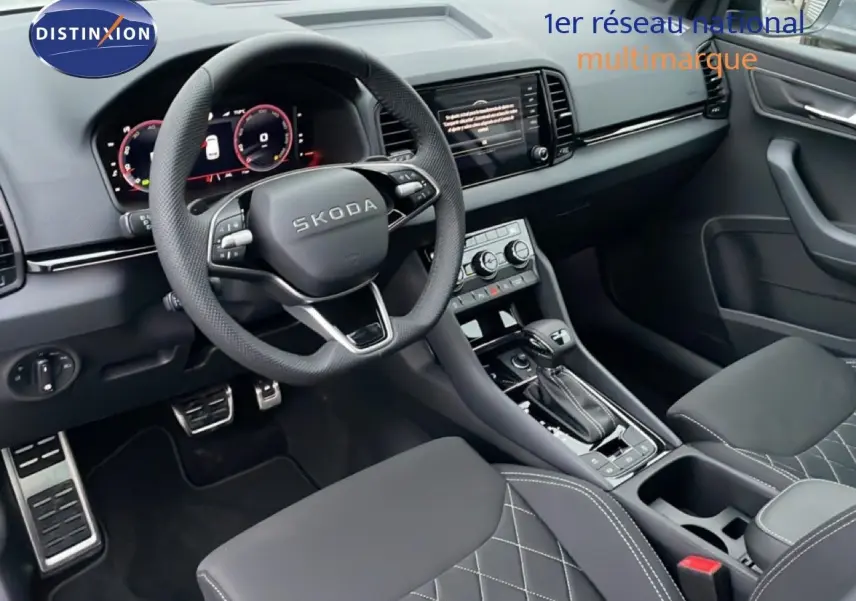 Vue intérieure côté conducteur du Skoda Karoq gris argent, avec volant multifonction et console centrale moderne.