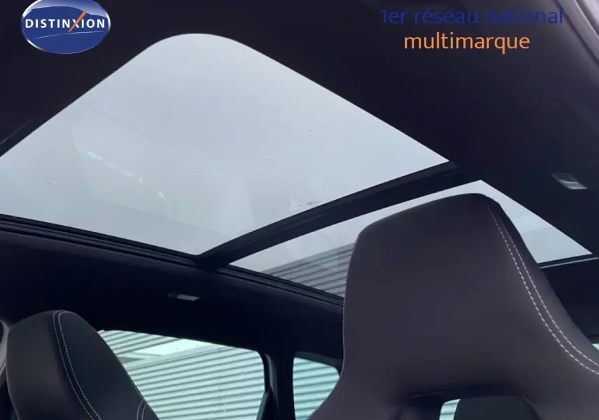 Toit panoramique ouvert vu de l'intérieur d'un Skoda Karoq gris argent 2025, sièges avant en cuir noir.