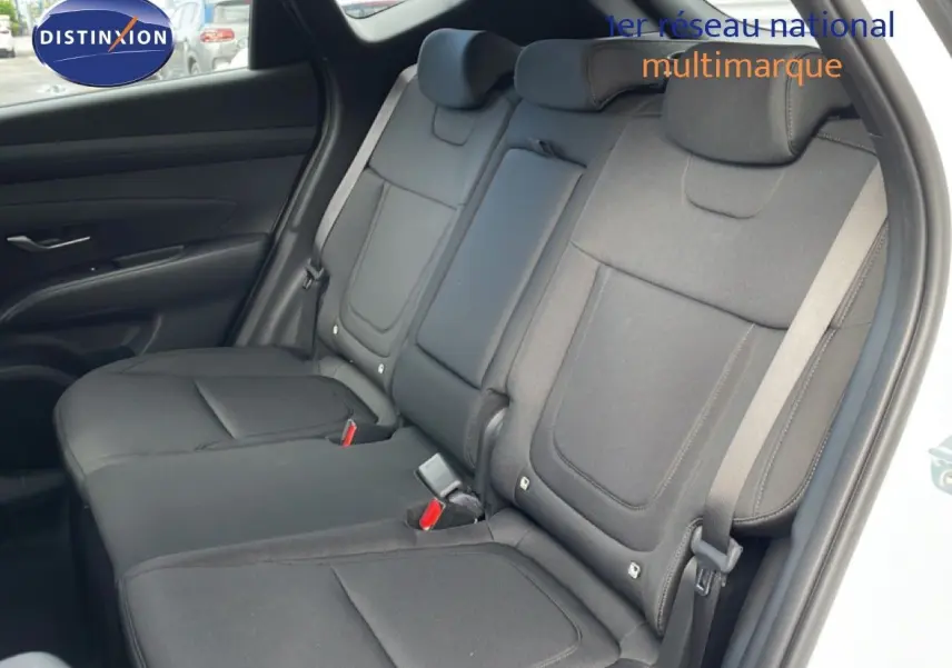 Vue intérieure montrant les sièges arrière en tissu noir du Hyundai Tucson blanc Atlas, avec ceinture de sécurité visible côté droit.