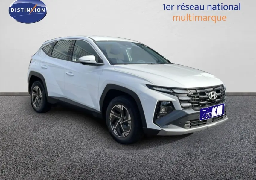 Hyundai Tucson blanc atlas en 3/4 avant droit, avec calandre noire distinctive et jantes bi-ton.