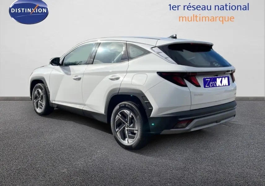 Vue 3/4 arrière droite du Hyundai Tucson blanc Atlas avec jantes bi-ton et vitres teintées.