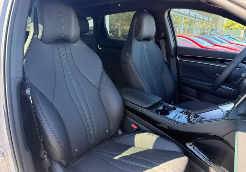 Vue intérieure avant du BYD SEAL U 1.5 DM-i 218ch Boost, sièges cuir noirs avec surpiqûres vertes et console centrale élégante.