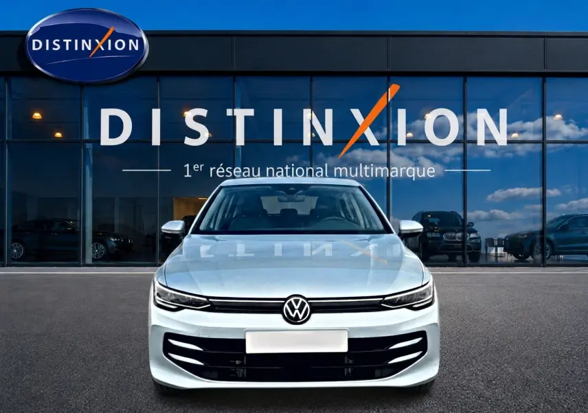Vue avant d'une Volkswagen Golf 1.5 etsi evo2 116 life dsg7 bleu glacier, devant une vitrine avec logo Distinxion.