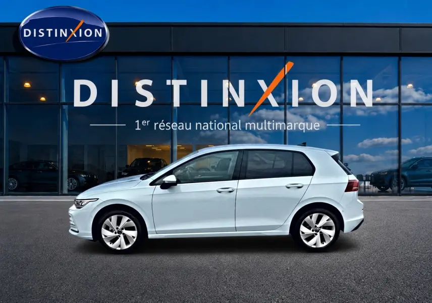 Volkswagen Golf 2026 bleu glacier vue de profil côté gauche devant une vitrine avec logo Distinxion.