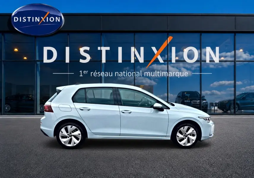 Vue latérale droite d'une Volkswagen Golf 1.5 etsi evo2 116 life dsg7 bleu glacier stationnée devant une vitrine Distinxion.