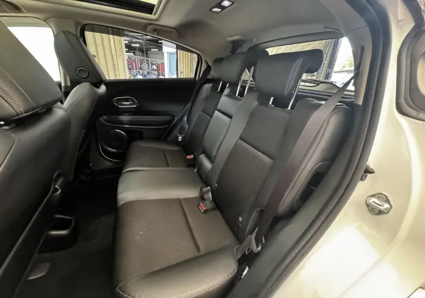 Vue intérieure côté droit sur la banquette arrière en cuir noir du Honda HR-V blanc, avec ceinture de sécurité attachée.