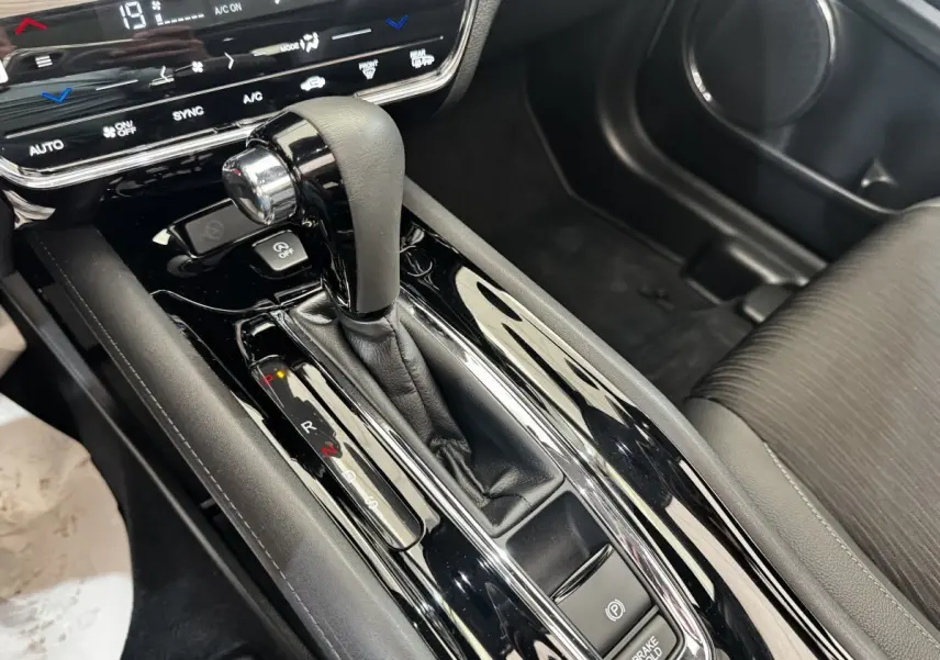 Gros plan sur la console centrale noire brillante du Honda HR-V 1.5 i-VTEC 130, levier de vitesse et frein électrique visibles.