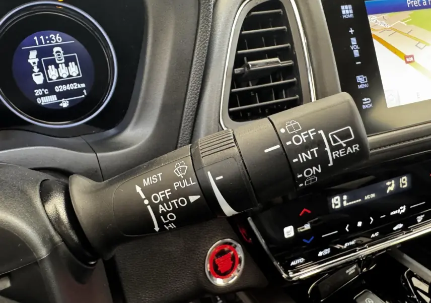 Gros plan sur la commande d’essuie-glace du tableau de bord noir du Honda HR-V blanc, avec écran tactile et bouton start rouge.