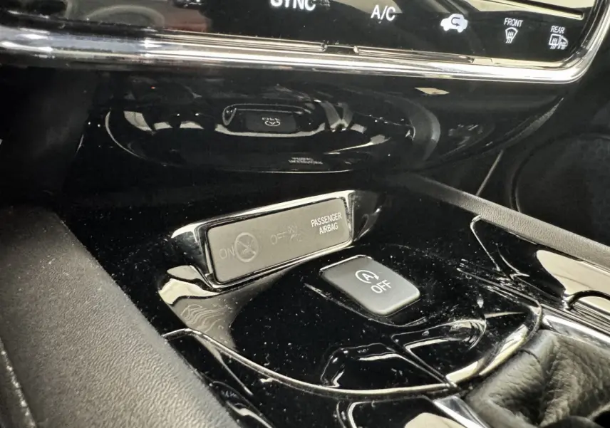 Gros plan sur la console centrale noire brillante du Honda HR-V 2019, avec bouton arrêt auto start-stop et indicateur airbag passager.
