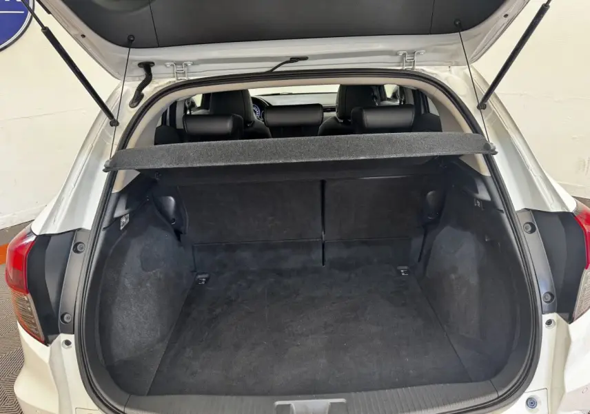 Vue arrière ouverte du coffre noir d'un Honda HR-V blanc 2019, avec tablette cache-bagages relevée.