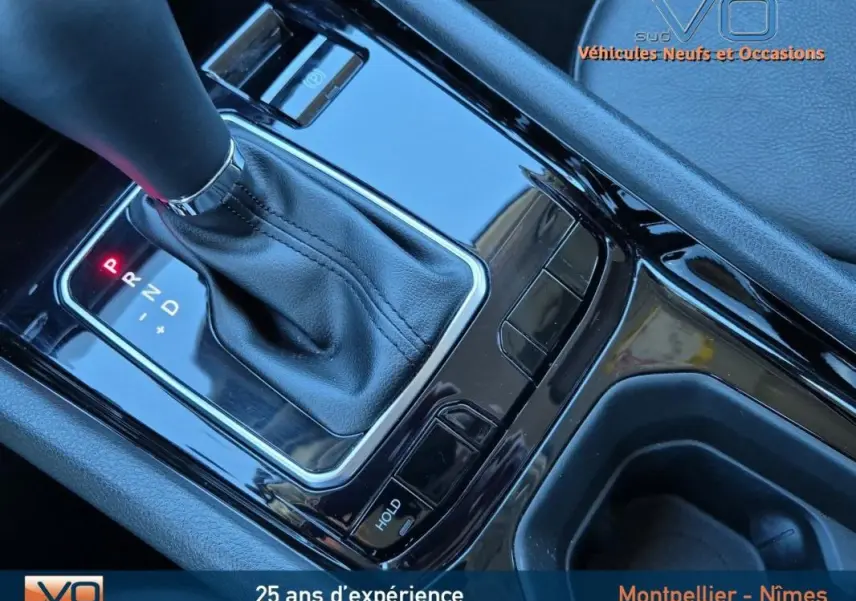 Gros plan sur la console centrale noire brillante du Jeep Compass gris 2024 avec levier de vitesse automatique et accoudoir.