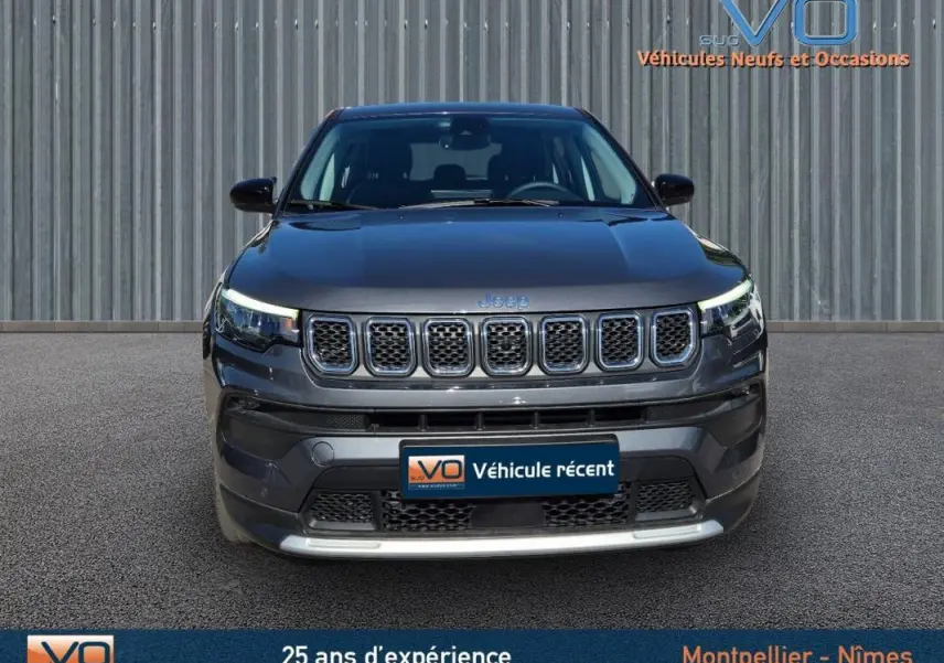 Vue frontale d'un Jeep Compass gris 2024 avec calandre distinctive et phares LED allumés.
