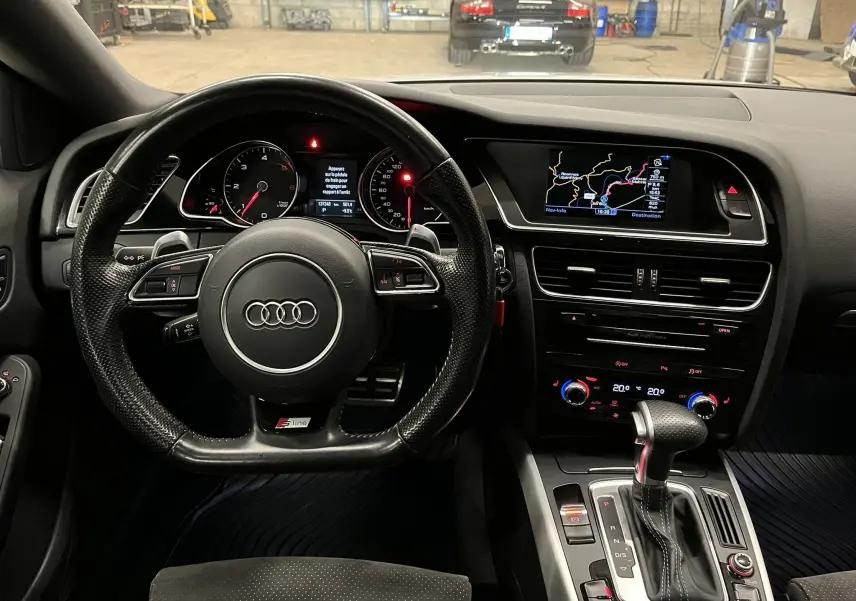 Vue intérieure centrée sur le volant S Line et la console centrale avec écran de navigation de l'Audi A5 Sportback 2015.