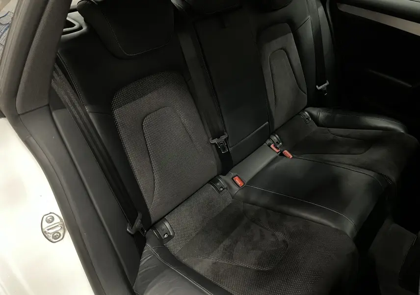 Vue intérieure de la banquette arrière noire en cuir et alcantara de l'Audi A5 Sportback blanche, côté gauche ouvert.