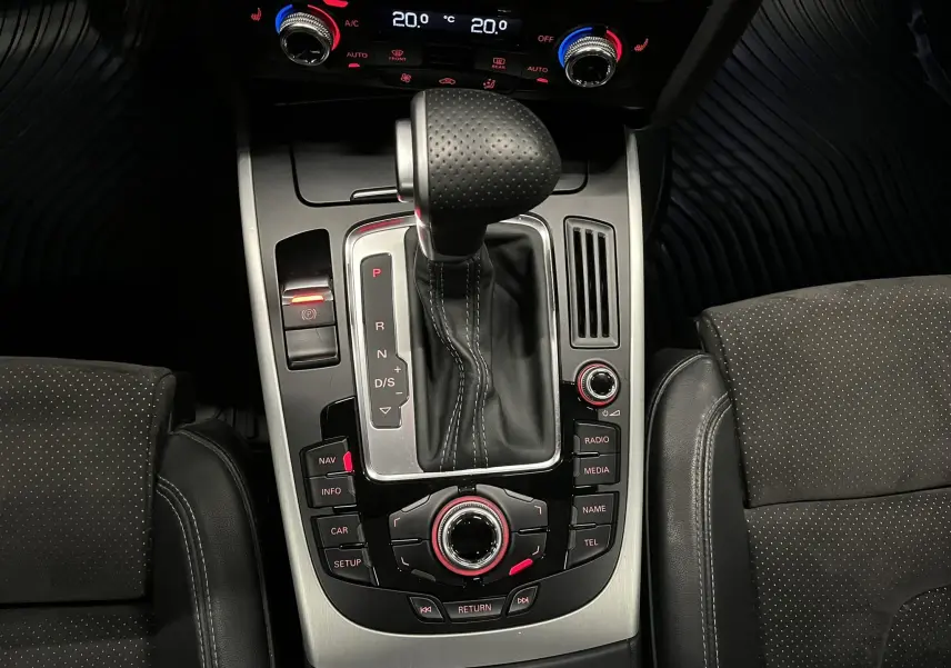 Vue plongeante sur la console centrale de l'Audi A5 Sportback blanche, mettant en valeur le levier de vitesse automatique et les commandes multimédia.