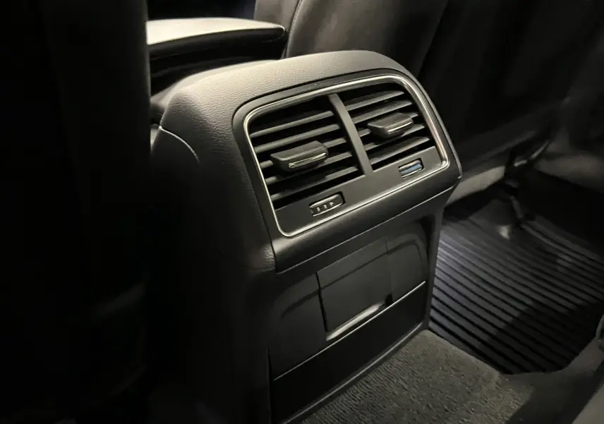 Vue rapprochée des aérateurs arrière noirs et des prises USB dans l’habitacle sombre de l’Audi A5 Sportback blanche.