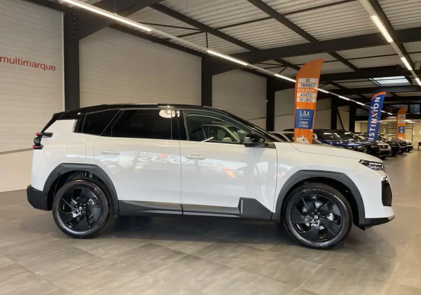 Vue profil droit d'un Citroën C5 Aircross blanc Okenite avec toit noir et jantes alliage noires en showroom.