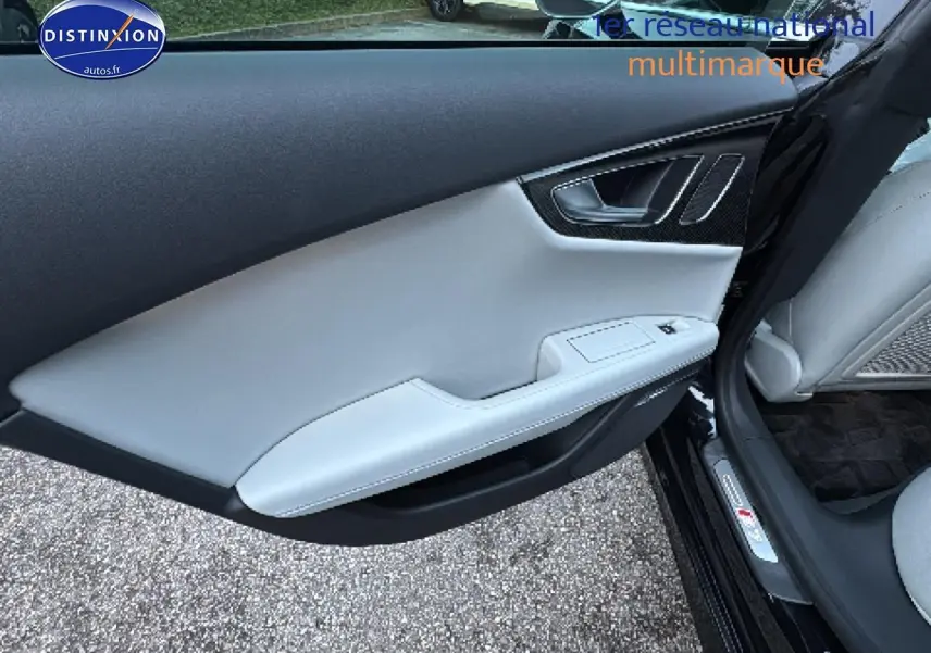 Vue intérieure côté gauche de la porte avant d’une Audi S7 Sportback noire avec garniture cuir claire et insert carbone.