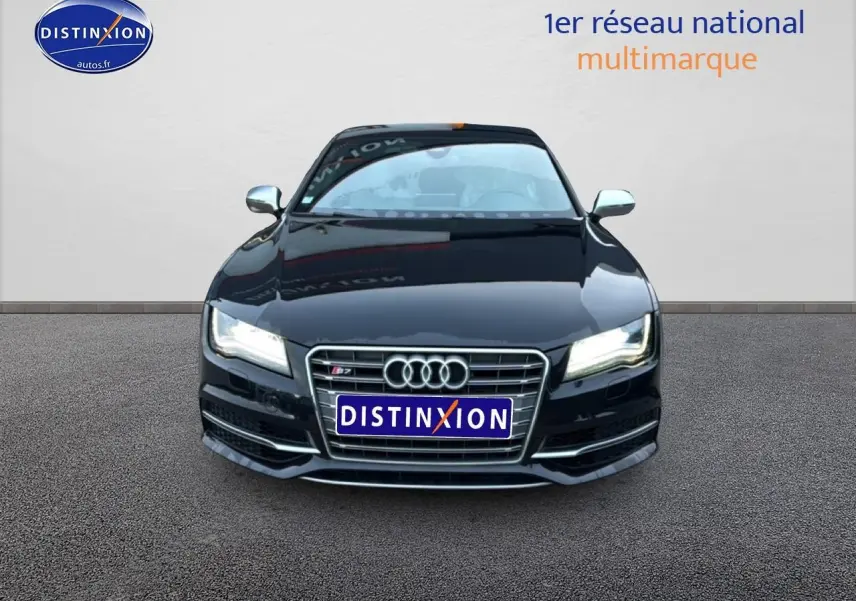 Vue de face d'une Audi S7 Sportback noire avec calandre chromée et phares allumés sur fond neutre.