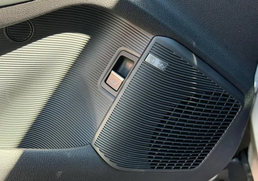 Gros plan sur le haut-parleur Infinity noir et la commande d'ouverture du coffre côté gauche intérieur du BYD SEAL U 2026.