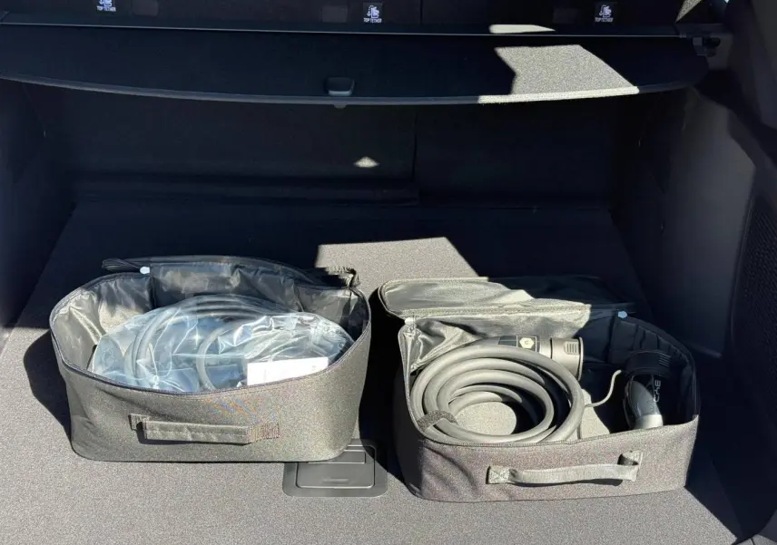 Coffre ouvert d’un BYD SEAL U 1.5 DM-i 324ch Design AWD 2026, montrant les câbles de recharge rangés dans des sacs noirs.