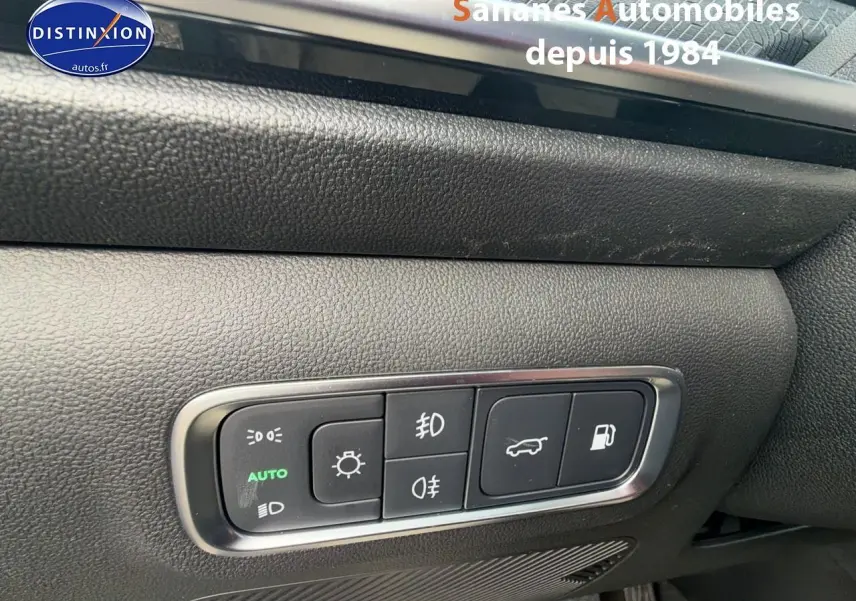 Gros plan sur les commandes d’éclairage et d’ouverture du coffre du JAECOO J7 1.5 PHEV vert olive, intérieur noir.