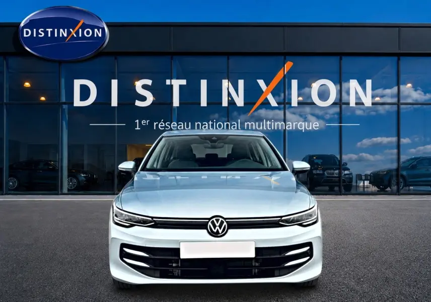 Vue frontale d'une Volkswagen Golf 1.5 etsi evo2 116 life dsg7 bleu glacier, devant une vitrine Distinxion.