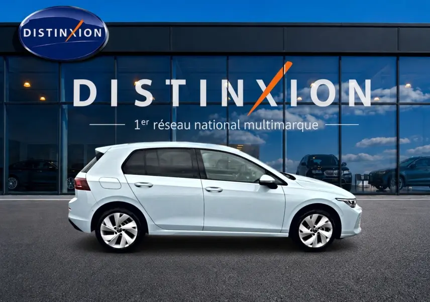 Vue latérale droite d'une Volkswagen Golf 1.5 etsi evo2 116 life dsg7 bleu glacier devant une vitrine Distinxion.