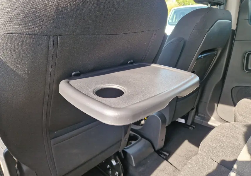 Tablette rabattable avec porte-gobelet fixée au dossier du siège avant droit dans l'habitacle du Citroën Berlingo gris Artense.