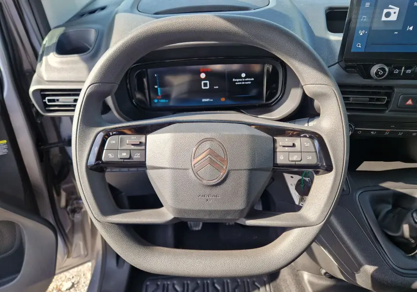 Vue rapprochée du volant gris du Citroën Berlingo 2025 avec commandes intégrées et tableau de bord numérique.