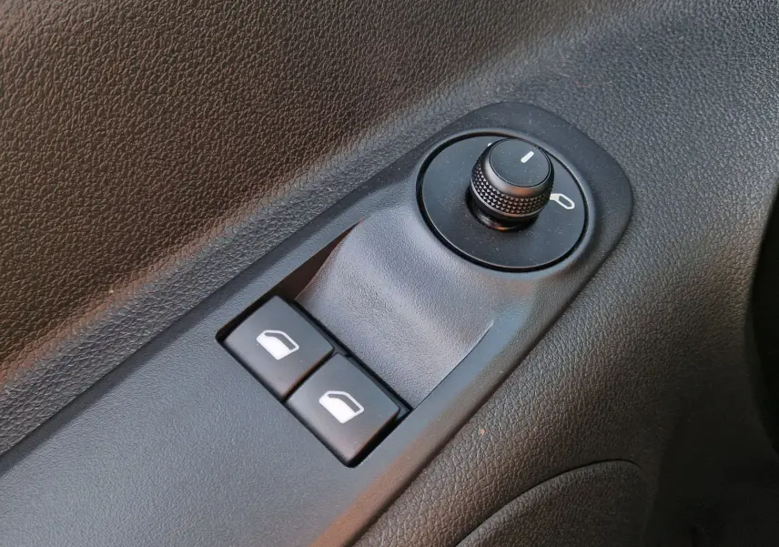 Gros plan sur les commandes de réglage des rétroviseurs et des vitres électriques côté conducteur du Citroën Berlingo gris Artense 2025.