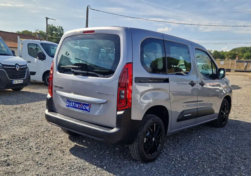 Vue 3/4 arrière droite du Citroën Berlingo gris Artense avec jantes noires et grille de séparation visible à l'intérieur.