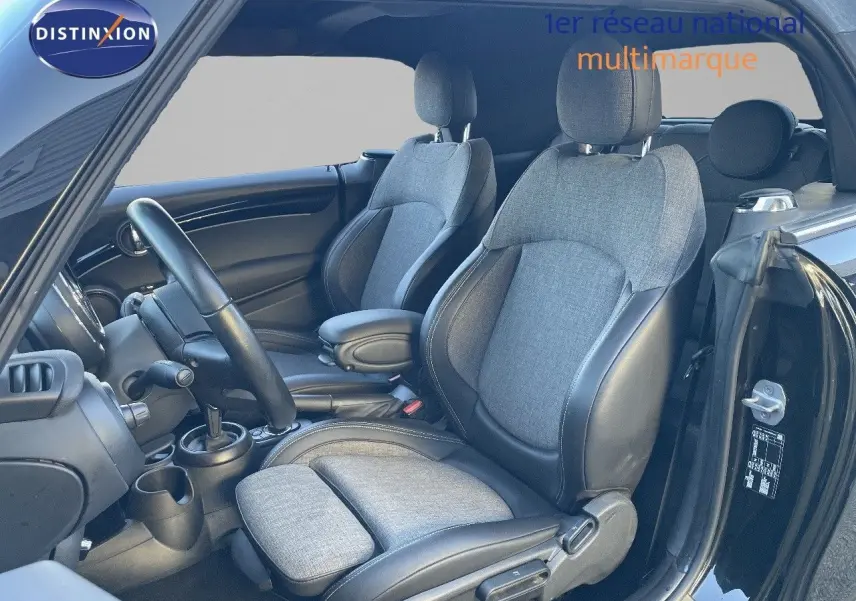 Vue intérieure côté conducteur de la MINI Cabriolet noire, mettant en valeur les sièges tissu gris et cuir noir.
