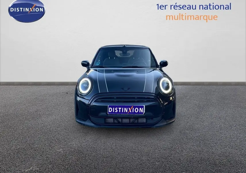 Vue frontale d'une MINI Cabriolet F57 noir midnight metal avec phares LED allumés et capot à bandes blanches.