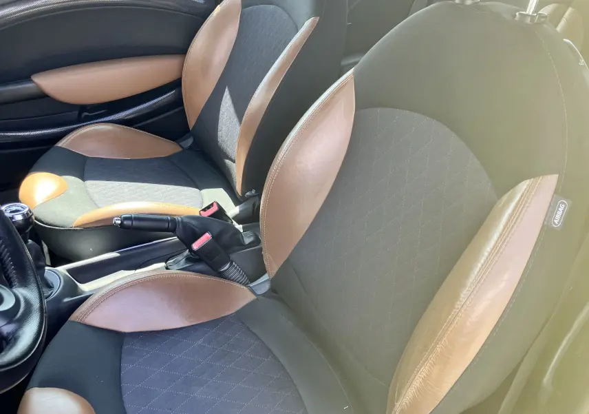 Vue rapprochée des sièges avant marron et noir en tissu et cuir dans l'habitacle d'une MINI Cooper S R56 de 2012.